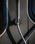 Close up of Tactic Engineering magnetic shower mount holding a stainless steel shower head and flexible hose on carbon fiber surface, neodymium magnet base provides secure attachment for outdoor van shower setup, included in the Ultimate Magnetic Accessories Bundle