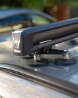 Tactic Engineering magnetic mounts holding Thule SnowPack ski rack on car roof, close up showing aerospace aluminum crossbar and rubber coated neodymium magnets. Mini Clubman