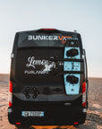 Rear view of BunkerVan Ford Transit with Duotone kiteboards magnetically mounted on back doors using Tactic Engineering magnetic carrier, parked on desert beach at sunset