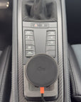 Tactic Engineering MagSafe Qi2 phone mount in the open centre console tray of a Porsche 718 with carbon fiber trim and PDK Sport buttons, no drilling