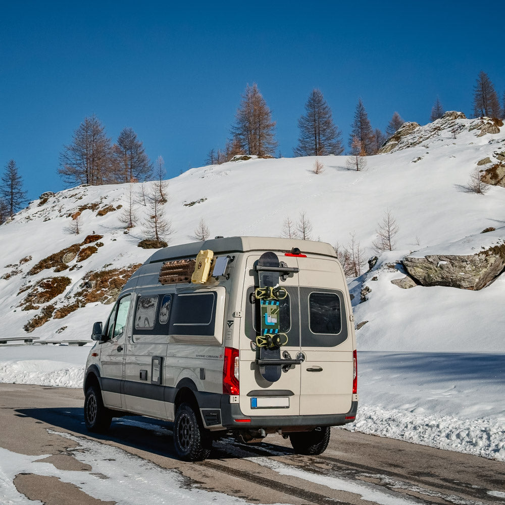 Magnetic ski and snowboard carrier mounted on the rear of a camper van in the Swiss Alps