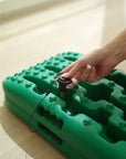 Hand demonstrating Tactic Engineering magnetic quick release mount installation on a green TRED recovery board, pressing the quick release pin through the board hole for tool free magnetic mounting