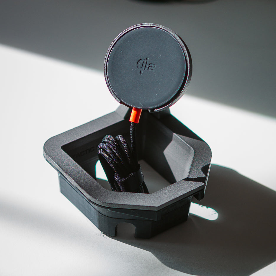 Tactic Engineering 2024 Toyota Land Cruiser 250 MagSafe phone mount with the McDodo Qi2 wireless charging puck upright on its industrial nylon arm and USB-C cable neatly stowed in the cupholder base — designed and manufactured in Switzerland