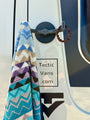 Tactic Engineering magnetic towel hook mounted on van exterior holding a colorful patterned beach towel, featuring neodymium magnet base with 55 kg pull force and rubber coated design for van life