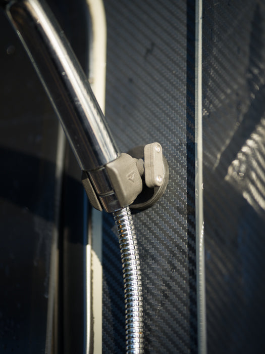 Tactic Engineering magnetic shower head holder close up showing the adjustable bracket and neodymium magnet base mounted on dark van exterior panel with shower hose connected