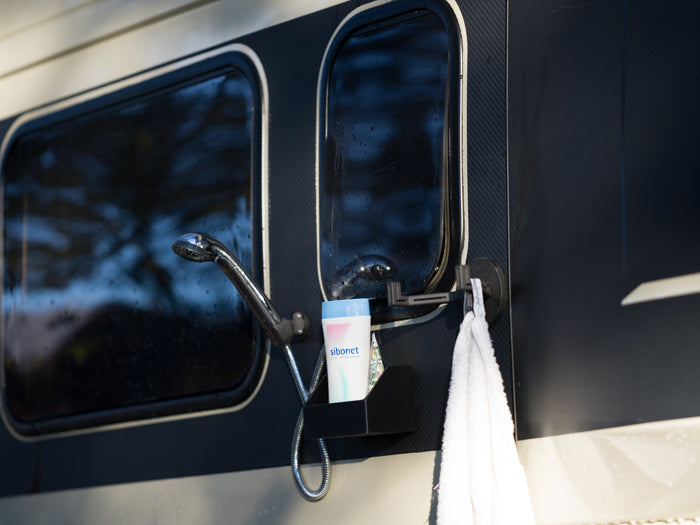 Tactic Engineering complete magnetic outdoor shower kit in use on van exterior showing magnetic shower head holder, magnetic shampoo bottle holder and magnetic towel hook all attached to vehicle body