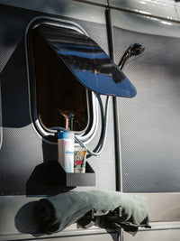 Tactic Engineering complete magnetic outdoor shower kit installed on van, showing magnetic shower head holder, shampoo holder with toiletries, and towel hook mounted on vehicle exterior