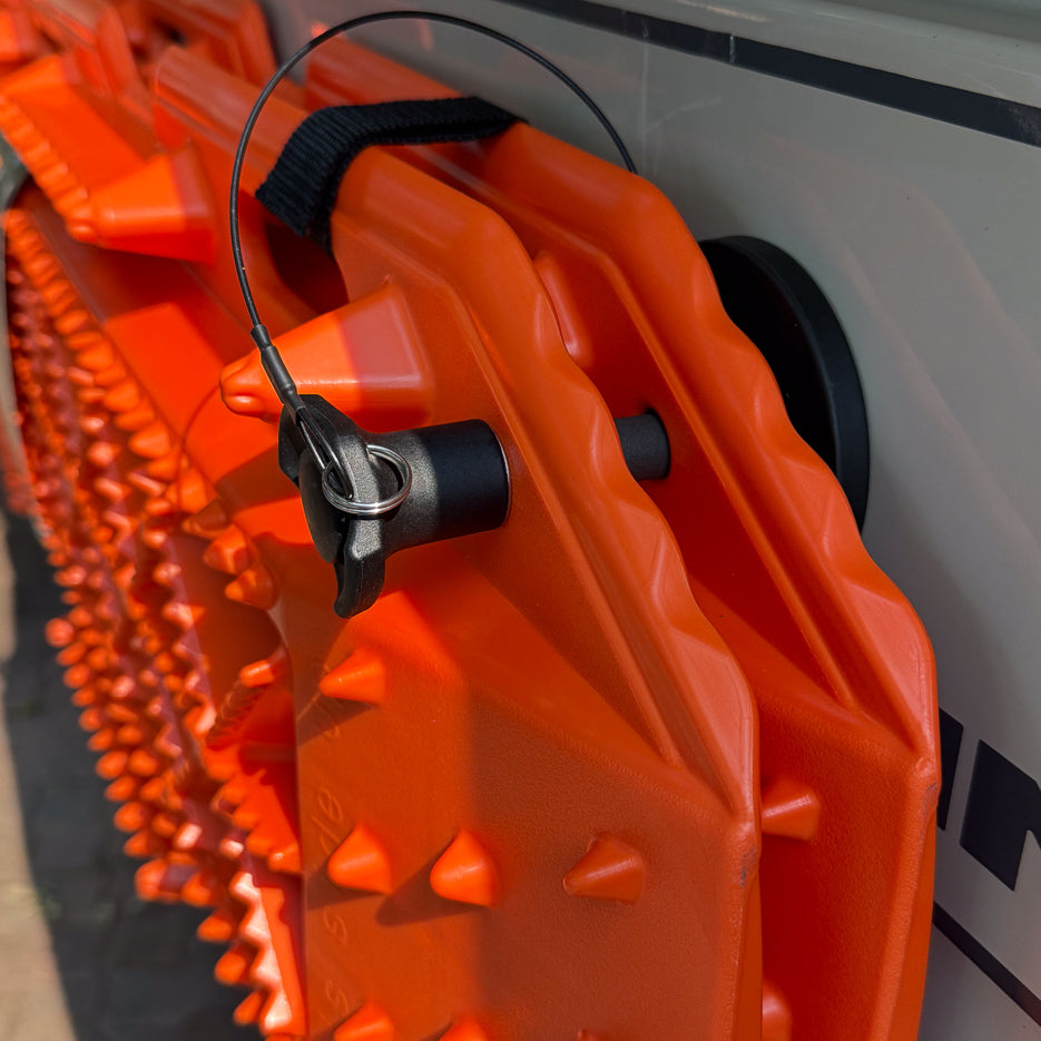 Close-up of a Tactic Engineering quick-release pin and rubber-coated neodymium magnet holding a Sumex recovery board against a white van body