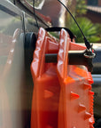 Quick-release pin with stainless ring and safety cable securing a Sumex recovery board to a van panel