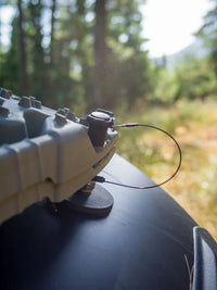 Tactic Engineering TRED magnetic mounts installed on curved vehicle body panel with anti theft cable, holding TRED recovery board securely with 55 kg pull force neodymium magnets in forest setting