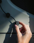 Hand placing Tactic Engineering Mini Clip magnetic cable holder on van interior panel, showing the compact clip holding a black cable in place with Tactic Engineering logo visible, demonstrating easy magnetic installation for campervan cable management