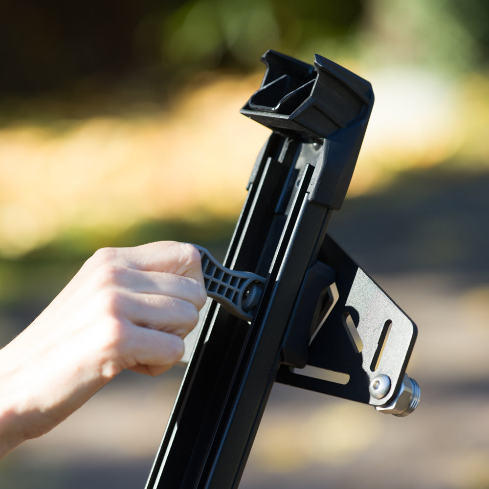 Person adjusting a black metal bracket to mount Snowboards and Skis on vehicles with magnets