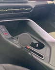 Magnetic Qi2 phone mount installed in the Cupra Terramar 2024 centre console. The charging head sits in the front cupholder beside the hazard and drive mode buttons. No drilling. No adhesive. Made in Switzerland.