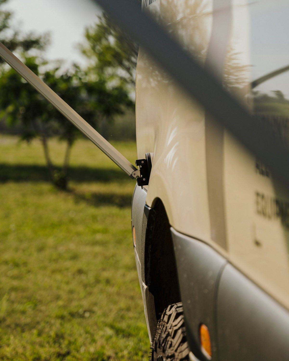 Detail view of Tactic Engineering magnetic awning support holding the Fiamma awning arm against the side panel of the Weinsberg X-Pedition 4x4 Sprinter by Ferrigato Camper