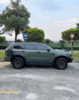 Dark green Ford Everest 4x4 side profile with off road tires parked on paved area, vehicle equipped with Tactic Engineering magnetic RotoPax mounting plate for fuel and water containers, trees and greenery in background