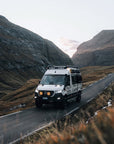 Mercedes Sprinter 4x4 z trapami MaxTrax na magnetycznych uchwytach szybkiego montażu Tactic Engineering, górska droga na Wyspach Owczych o zmierzchu