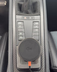 Tactic Engineering MagSafe Qi2 phone mount installed in the open centre console tray of a Porsche 718 with carbon fiber trim and PDK Sport buttons, no drilling