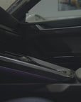 Installing the Tactic Engineering magnetic phone mount in a Porsche 911 (992). The mount sits in the centre-console storage bucket beside the gear selector, the phone attaches magnetically to the Qi2 charging head, and the screen stays upright and readable. No drilling. No adhesive. Made in Switzerland.
